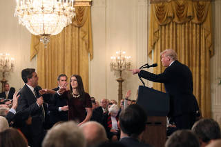 A White House staff member reaches for the microphone held by CNN's Jim Acosta as he questions U.S. President Donald Trump during a news conference in Washington