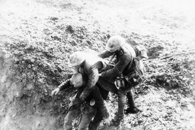 Um soldado canadense ajuda um militar alemão ferido a ser levado a um local seguro