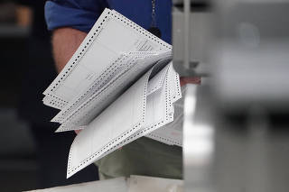 A worker holds ballots before a ballot recount in Lauderhill