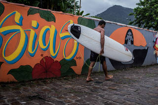 Surfista caminha pelo novo Beco da Mulher Maravilha, em Maresias (SP)