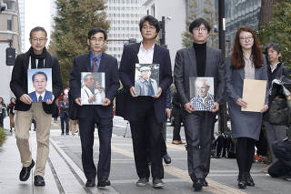 Lawyers and activists hold photos of South Korean plaintiffs who were forced to work for a Japanese firm during World War Two as they visit Nippon Steel & Sumitomo Metal Corp's headquarters building in Tokyo