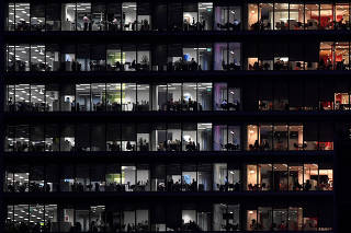 FILE PHOTO: Workers are seen in an office tower in the Canary Wharf financial district at dusk in London