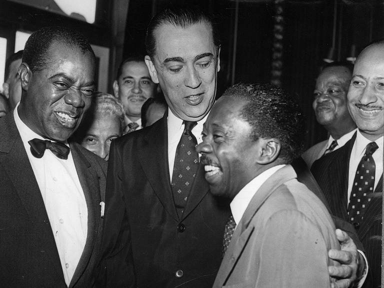 O ator Grande Otelo com o presidente Juscelino Kubitschek e o jazzista Louis Armstrong durante almoço no Rio oferecido pelo presidente ao músico norte-americano