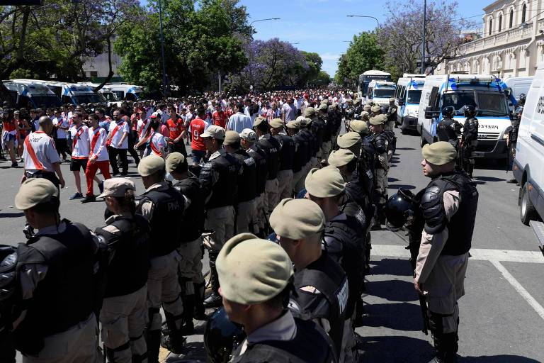 Policiais fazem corredor para a passagem de torcedores do River Plate antes do adiamento da final da Libertadores neste domingo (25)