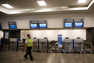 An airport security officer walks in front of a closed counter of Argentina's state-owned airline Aerolineas Argentinas during a 24-hour strike, at Buenos Aires airport