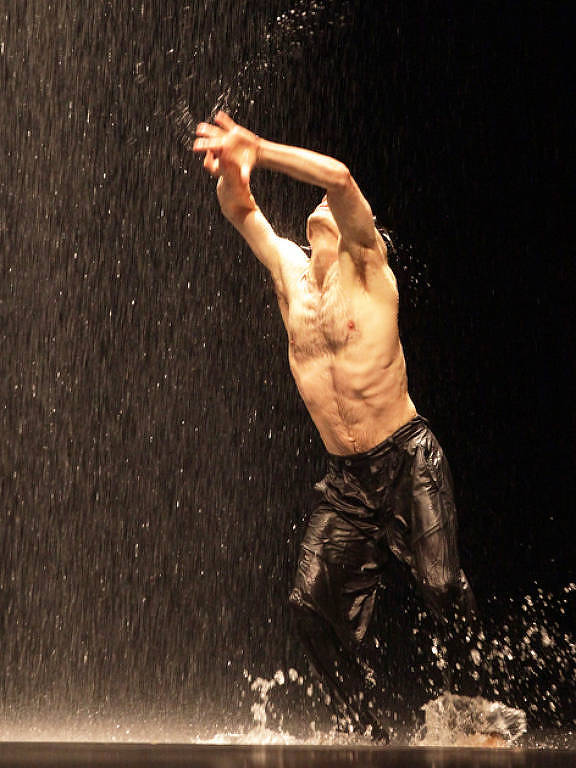 um bailarino sem camisa e com calça preta molhado