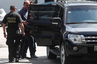 Rio de Janeiro governor Luiz Fernando Pezao is escorted by a policeman at the Federal Police headquarters in Rio de Janeiro