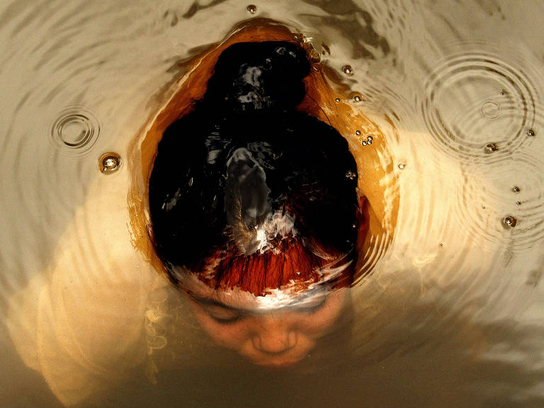 Mulher quilombola submersa na água de um rio