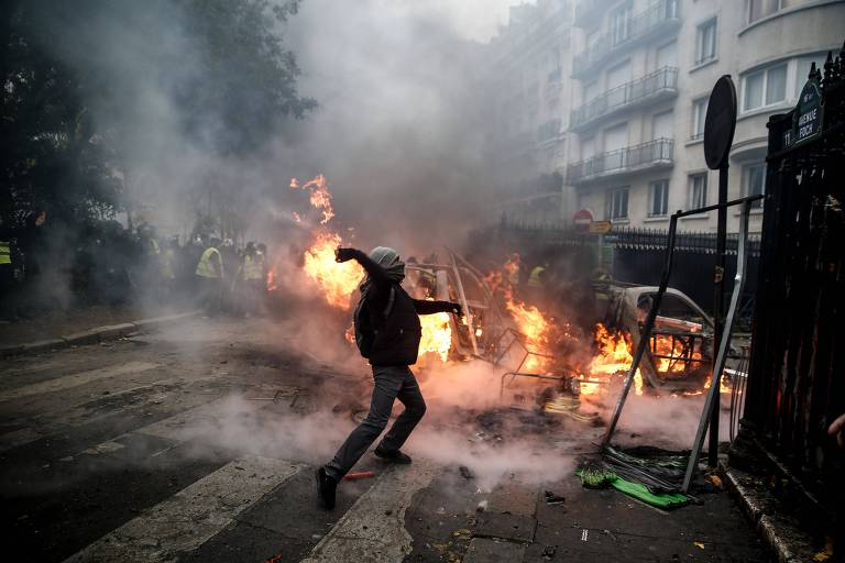Manifestante joga projétil na polícia em mais um dia de protesto dos 'coletes amarelos' contra o aumento do preço do combustível e o alto custo de vida em Paris
