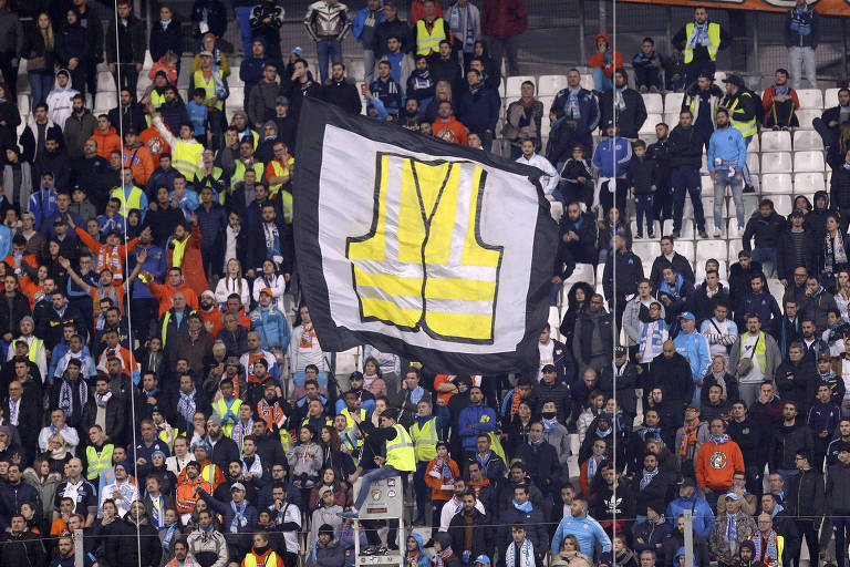 Apoiadores levantam bandeira com um 'colete amarelo' gigante, em solidariedade aos protestos contra o aumento das taxas de combustível, durante o jogo de futebol entre Marselha e Reims, no estádio Velodrome. em Marselha, sul da França