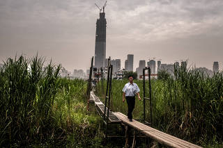 A man walks along an elevated gangway in Wuhan, a former river town that has swelled into a metropolis of over 10 million, in the Hubei province of China.