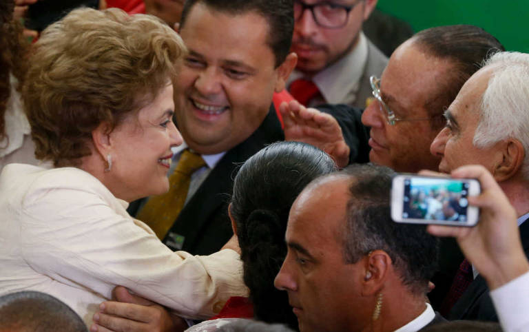A então presidente Dilma Rousseff cumprimenta o deputado Paulo Maluf (PP-SP) em cerimônia em que o ex-presidente Lula tomou posse como ministro da Casa Civil, durante a crise do governo da petista, que levaria a seu impeachment; mais tarde, ele votaria pelo afastamento de Dilma