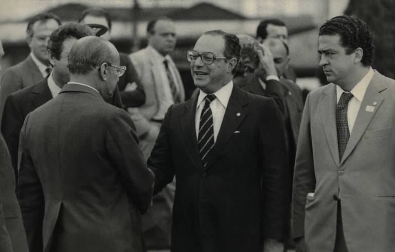 O então governador de São Paulo, Paulo Maluf, cumprimenta o presidente Figueiredo. Maluf foi responsável pela forte repressão a greves de sindicatos no ABC, que levou à morte de um operário e a prisão de líderes grevistas, entre eles, Luiz Inácio Lula da Silva. Mais adiante, o governador se torna candidato do PDS (ex-Arena) à presidência