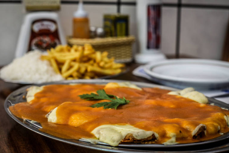 Coberto com generosas camadas de queijo e molho, o bife à parmigiana do Jhony's é o carro chefe da casa