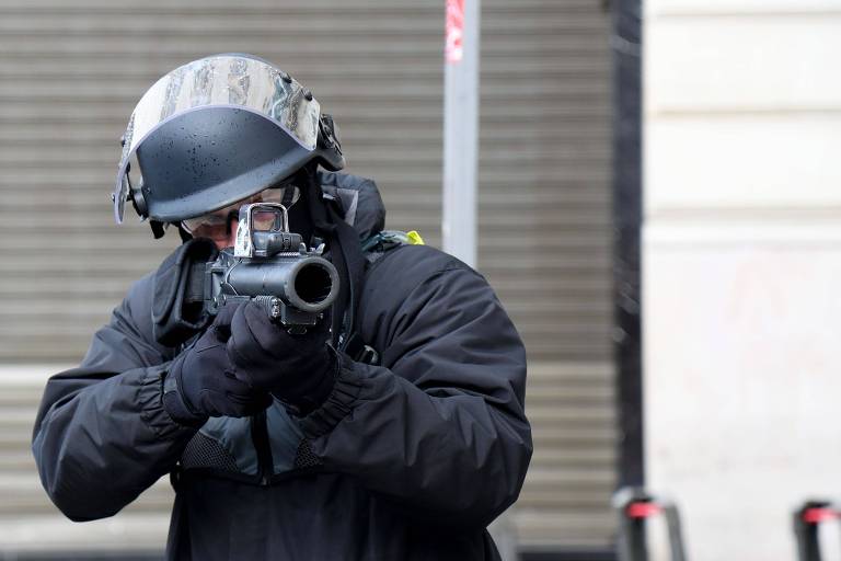 Policial aponta arma de bala de borracha contra manifestantes em Paris