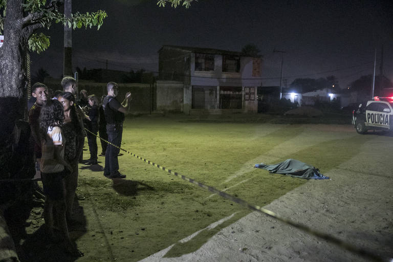 Policiais fazem perícia no corpo de Anderson Pereira Santos, 21, num pequeno campo de futebol na localidade conhecida como Marrocos, no bairro Bom Jardim, periferia de Fortaleza. Anderson não tinha antecedentes criminais e, segundo moradores do local, não morava por lá, mas estava visitando os pais quando foi abordado por sete homens em um carro e atingido com pelo menos sete tiros. polícia diz que Anderson pode ter sido executado por engano ou por ser irmão de um integrante de uma das facções criminosas que atuam em todo o estado do Ceará
