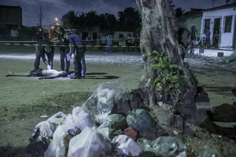 Policiais fazem perícia no corpo de Anderson Pereira Santos, 21, num pequeno campo de futebol na localidade conhecida como Marrocos, no bairro Bom Jardim, periferia de Fortaleza. Anderson não tinha antecedentes criminais e, segundo moradores do local, não morava por lá, mas estava visitando os pais quando foi abordado por sete homens em um carro e atingido com pelo menos sete tiros. polícia diz que Anderson pode ter sido executado por engano ou por ser irmão de um integrante de uma das facções criminosas que atuam em todo o estado do Ceará