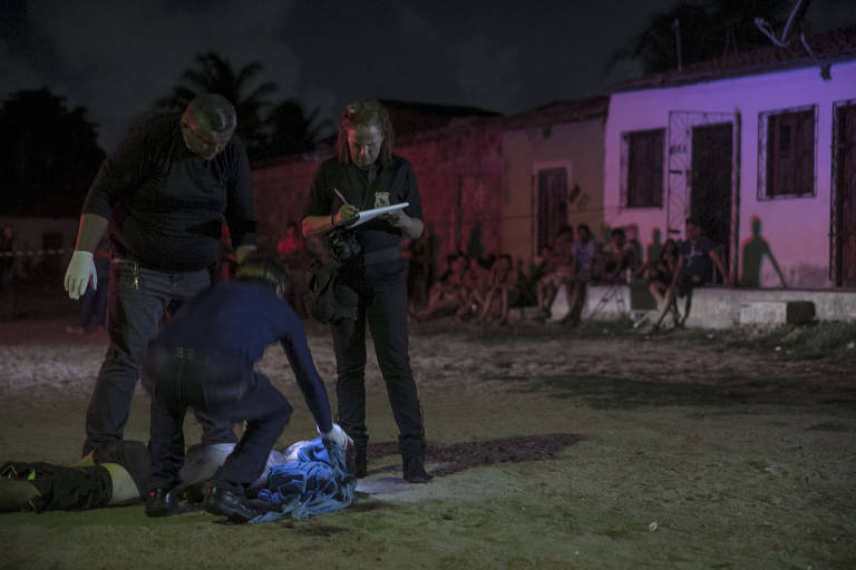 Policiais fazem perícia no corpo de Anderson Pereira Santos, 21, num pequeno campo de futebol na localidade conhecida como Marrocos, no bairro Bom Jardim, periferia de Fortaleza. Anderson não tinha antecedentes criminais e, segundo moradores do local, não morava por lá, mas estava visitando os pais quando foi abordado por sete homens em um carro e atingido com pelo menos sete tiros. polícia diz que Anderson pode ter sido executado por engano ou por ser irmão de um integrante de uma das facções criminosas que atuam em todo o estado do Ceará