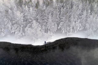Man fishes on Yenisei River covered with snow and hoarfrost outside Siberian city of Krasnoyarsk