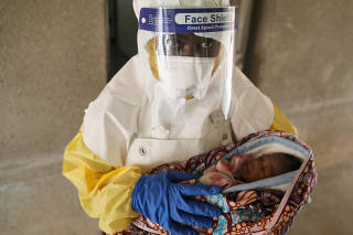 A health care worker carries a baby suspected of being infected with Ebola virus in a hospital in Oicha