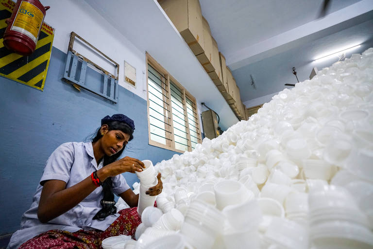 Funcionário em fábrica de plásticos em Chennai, Índia, separa copos descartáveis usados em refeições; a empresa produz 2 bilhões de items de uso único para marcas multinacionais e locais