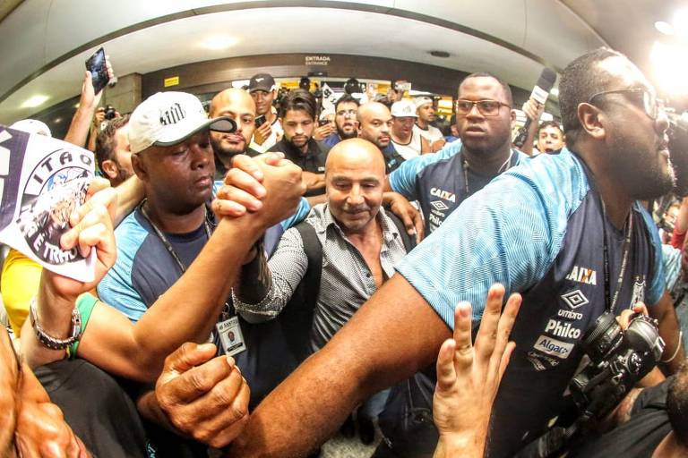 Cercado por seguranças e torcedores do Santos, o técnico argentino Jorge Sampaoli desembarca no Brasil