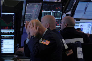 FILE PHOTO: A trader works at his post on the floor of the NYSE in New York