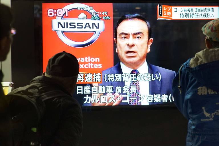 Pedestres olham para imagem de Carlos Ghosn na televisão; ele permanece no comando da Renault