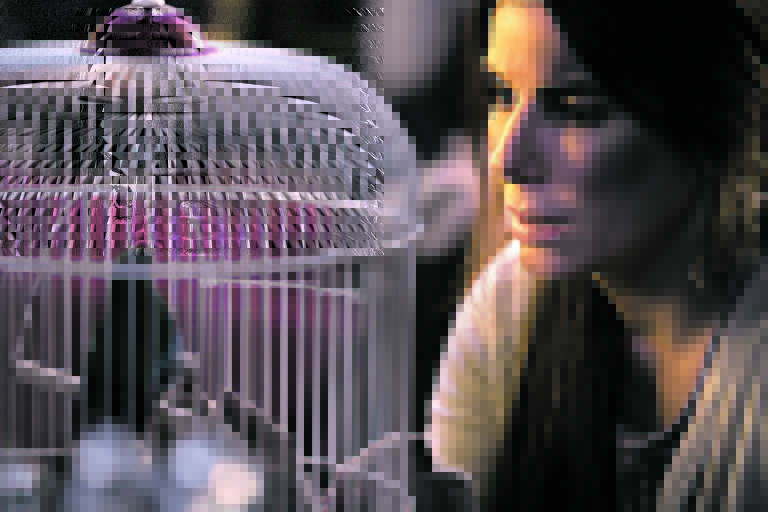 Sandra Bullock em cena de 'Bird Box',  que está desde sexta (21) na Netflix"Merrick Morton/Folhapress.
A personagem observa um pássaro preso em uma gaiola. 