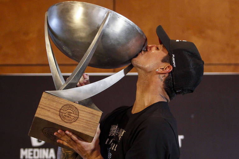 Medina beija o trofeu de campeão mundial de surfe durante coletiva no seu retorno ao Brasil