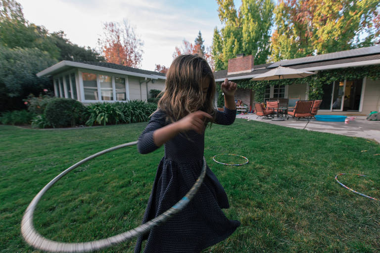 Filha de Kristin Stetcher brinca no quintal com um bambolê 