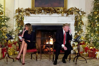 U.S. President Trump and the first lady participate in NORAD Santa tracker phone calls from children, in the State Dining Room of the White House in Washington