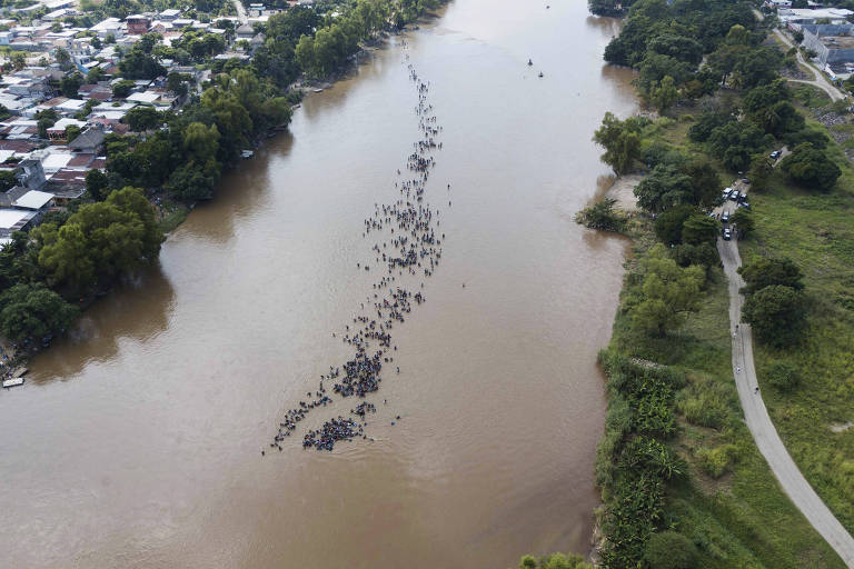 Imigrantes da América Central cruzam a pé o rio Suchiate, que conecta a Guatemala ao México, durante caravana; o grupo, o segundo a fazer a empreitada de tentar chegar aos EUA, foi impedido pelo governo mexicano de usar barcos e canoas para fazer a travessia do rio