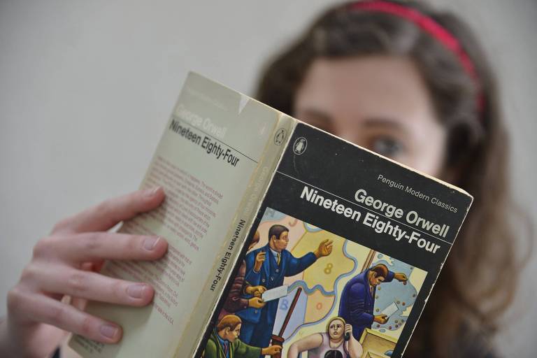Mulher segura o livro "1984", de George Orwell