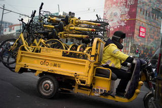 FILE PHOTO: A worker transports bicycles of the bike-sharing startup Ofo in Beijing