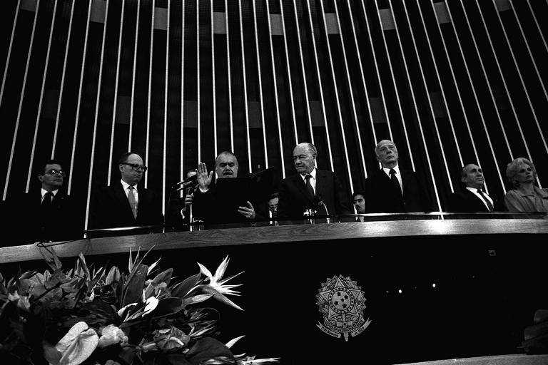 Com a mão direita levantada, dirigindo-se ao plenário do Congresso, Jose Sarney lê o juramento e toma posse