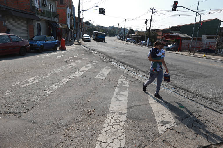Homem com criança caminha na avenida Sapopemba na zona leste da capital paulista