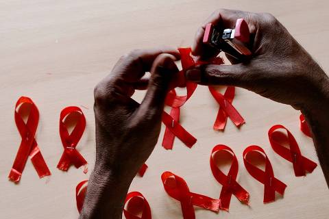 A HIV-positive person from the Support and Care Centre of the Sumanahalli Society prepares 'red ribbons' on the eve of World Aids Day in Bangalore on November 30, 2015.  Globally about 36.9 million people are living with HIV including 2.6 million children, while the global response to HIV has averted 30 million new HIV infections and nearly 8 million deaths since 2000.   AFP PHOTO/ Manjunath KIRAN ORG XMIT: MK006
