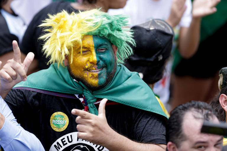 Sob um forte calor, os apoiadores que estão na Praça dos Três Poderes buscam se proteger do sol e se refrescar