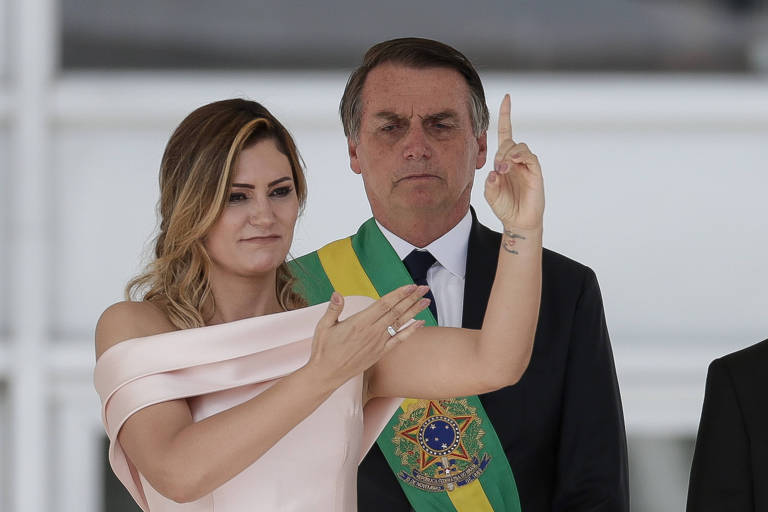 A primeira-dama, Michelle Bolsonaro, fez um discurso em Libras no Palácio do Planalto. Ela gesticula, observada pelo marido, Jair Bolsonaro