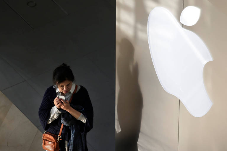 Mulher segura iPhone próxima à loja da Apple em Pequim, na China; iPhone responde por mais de 60% da receita da companhia 