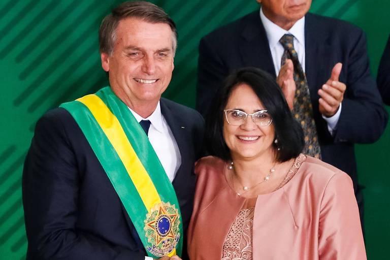 Jair Bolsonaro, com faixa presidencial, ao lado de Damares Alves