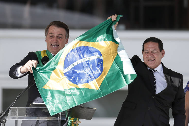 O presidente Jair Bolsonaro, ao lado do vice, general Hamilton Mourão, com a bandeira do Brasil na cerimônia de posse, no começo de 2019, no Palácio do Planalto, em Brasília
