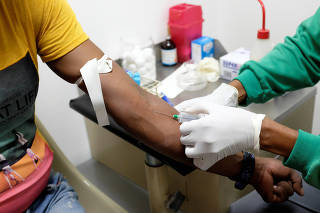 A nurse draws a blood sample for an HIV test at the lab of the NGO 