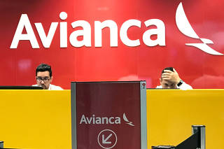 Employees are seen at the desk of Avianca airlines at Afonso Pena International Airport in Sao Jose dos Pinhais
