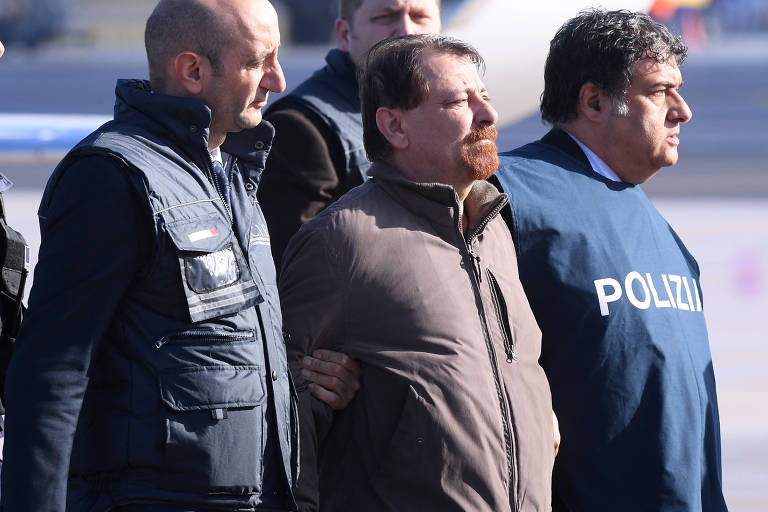 O ex-militante comunista italiano Cesare Battisti, escoltado por policiais italianos em sua chegada a Roma