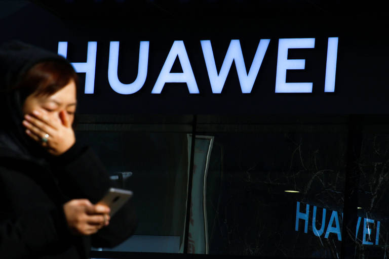 Mulher usa seu celular em frente à loja da Huawei em Pequim, na China 