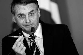 Brazil's President Jair Bolsonaro shows a pen during a signing ceremony of the decree which eases gun restrictions in Brazil, at the Planalto Palace in Brasilia
