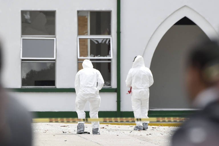 Especialistas trabalham na cena do ataque à escola de treinamento de policiais em Bogotá; janelas foram quebradas na explosão 