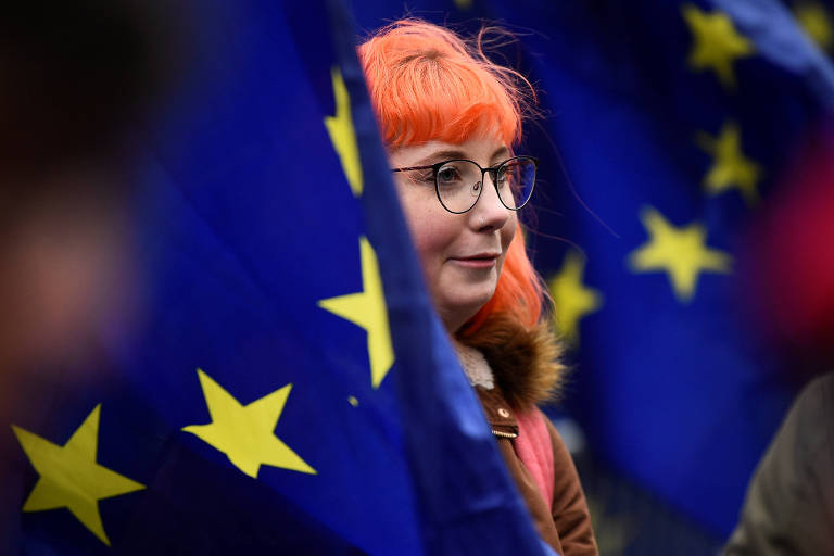 Mulher com bandeira da União Europeia em frente ao Parlamento britânico